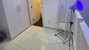 Ein Zimmer mit weißen Schränken, Fliesenboden, Klimaanlage und einer blauen Leuchte.