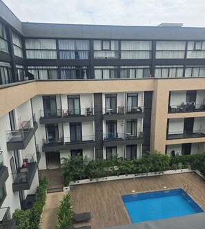 A multi-story building with balconies, a swimming pool, and outdoor seating areas. - ebs properties 2 two bedroom duplex (Accra)