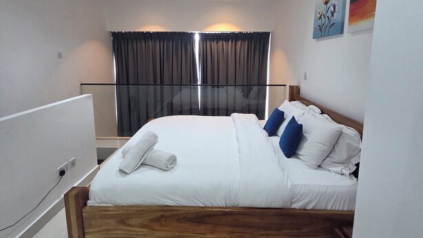 Ein modernes Schlafzimmer mit einem hölzernen Bett, weißer Bettwäsche und einem Fenster mit Vorhängen.
