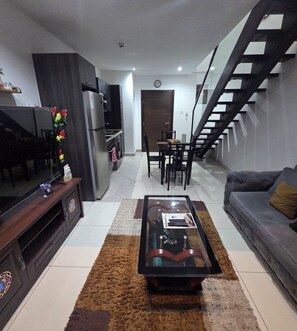 A modern living room with a sofa, coffee table, and a dining area with chairs and a table. - ebs properties 2 two bedroom duplex (Accra)