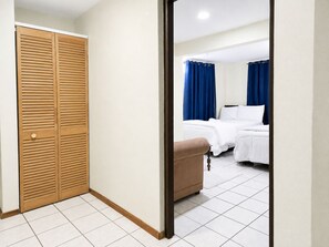 Ein Hotelzimmer mit einem Holzschrank, einem Bett mit weißer Bettwäsche und blauen Vorhängen.