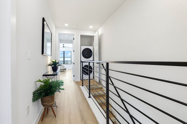 A modern hallway with a staircase, a potted plant, and a ceiling fan. - Unwind in Style: Luxe Condo Getaway! (New Braunfels)