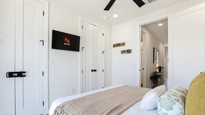 Una camera da letto con un letto, una TV fissata al muro e una porta con maniglia.
