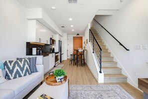 Ein modernes Wohnzimmer mit einer Couch, einem Couchtisch und einer Treppe, die zu einem Essbereich führt.