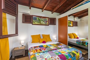 A hotel room with a large bed, two bedside tables, a mirror, and a window with shutters. - Beachfront Villa - Private Paradise (Le Robert)