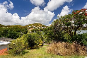 A coastal landscape with a hill, greenery, and a body of water. - Beachfront Villa - Private Paradise (Le Robert)
