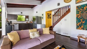 A modern living room with a sofa, a staircase, and a kitchen in the background. - Beachfront Villa - Private Paradise (Le Robert)
