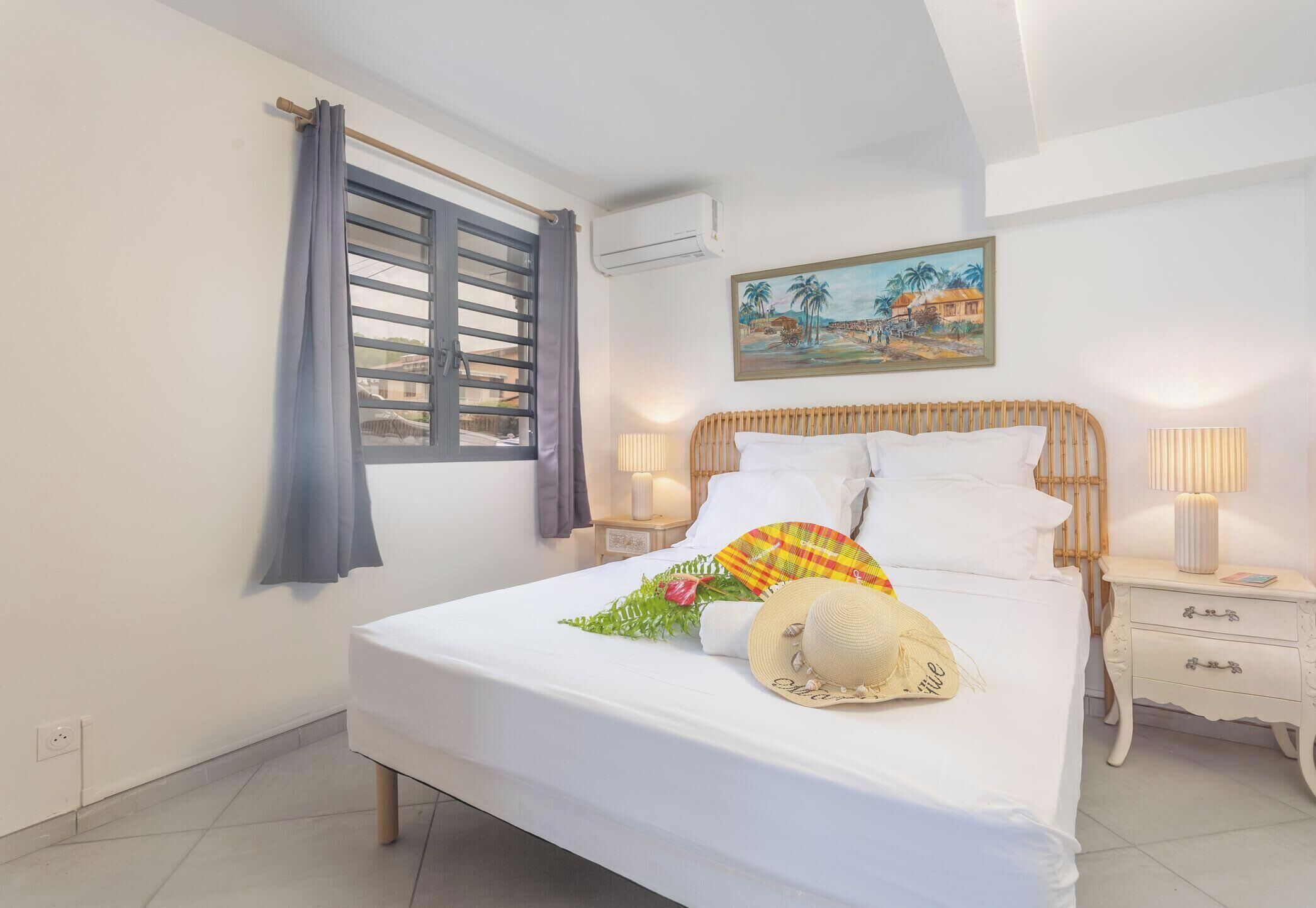 Une chambre d’hôtel avec un lit, une fenêtre avec des rideaux, un climatiseur fixé au mur, un tableau et des lampes de chevet.