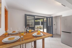 Eine moderne Küche mit einem Esstisch, gedeckt für das Frühstück, darunter Teller mit Essen, Gläser und ein Kühlschrank.
