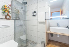 Ein modernes Badezimmer mit Duschkabine aus Glas, einem weißen Waschbecken und einem Spiegel.