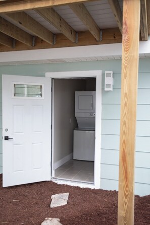 A small laundry room with a door, a washing machine, and a microwave. - The Nile (Fort Myers Beach)