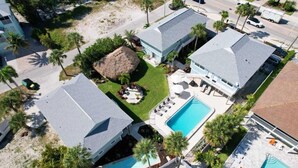 Un resort con varias construcciones, una piscina y una estructura de techo de paja.