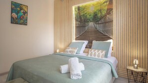 Une chambre à coucher avec un lit, des oreillers, une serviette, une table de chevet, une lampe et un tableau au mur.