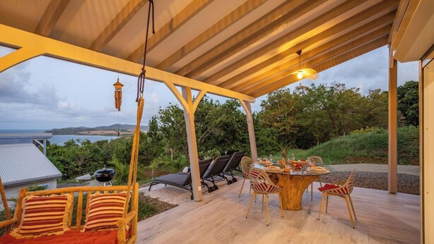 Un espace de restauration en plein air avec une table et des chaises, un luminaire suspendu et une vue sur le paysage.