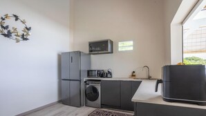 Une cuisine compacte équipée d’un réfrigérateur, d’un four à micro-ondes, d’une machine à café et d’un lave-linge.