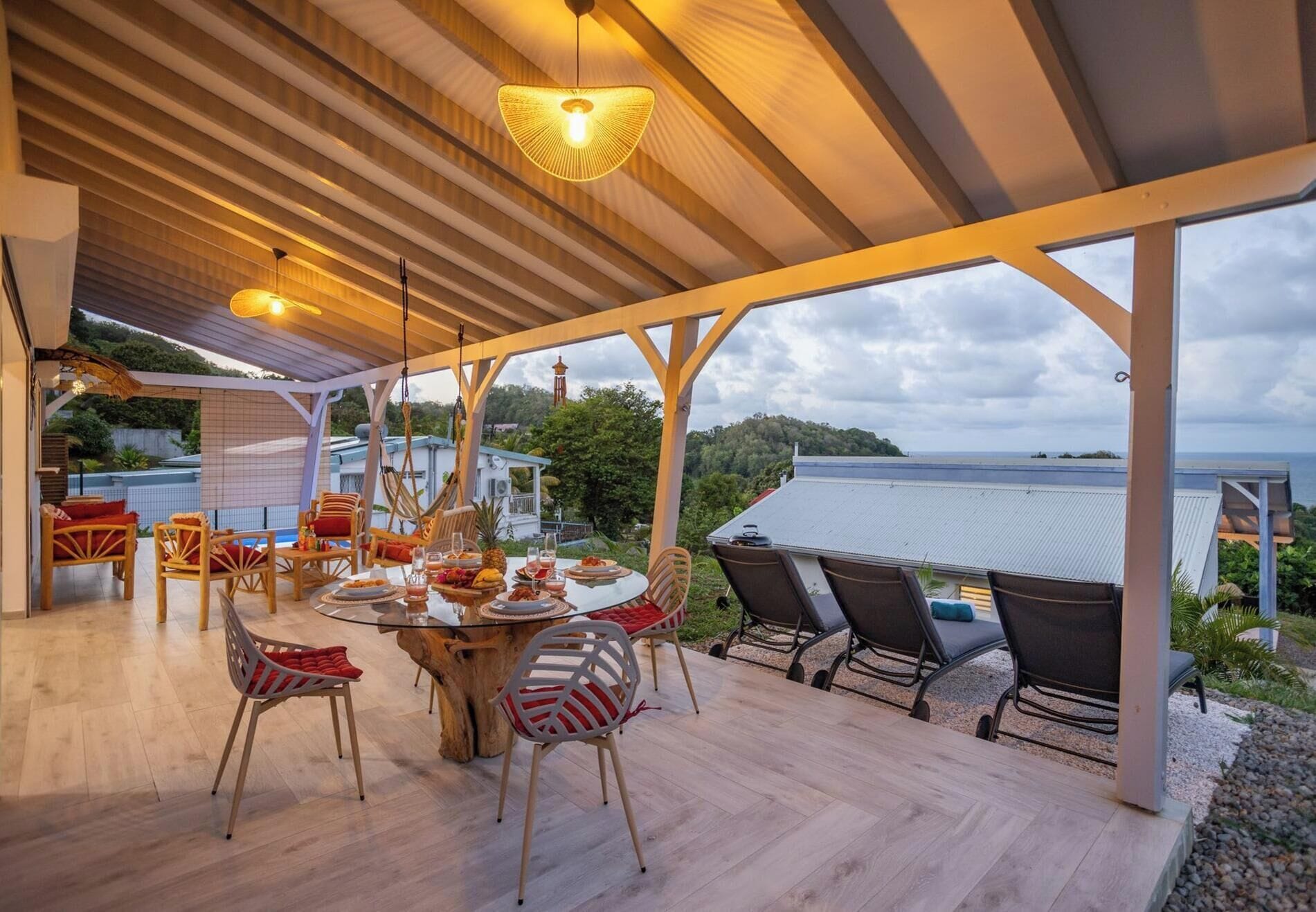 An outdoor covered patio with wooden flooring, a round table, and various seating options.