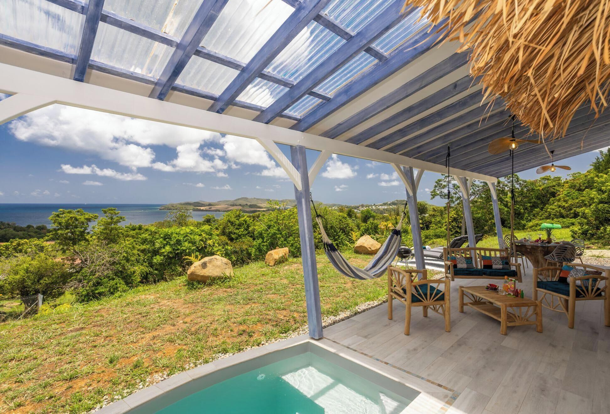 A covered outdoor area with a pool, seating, and a view of the sea.