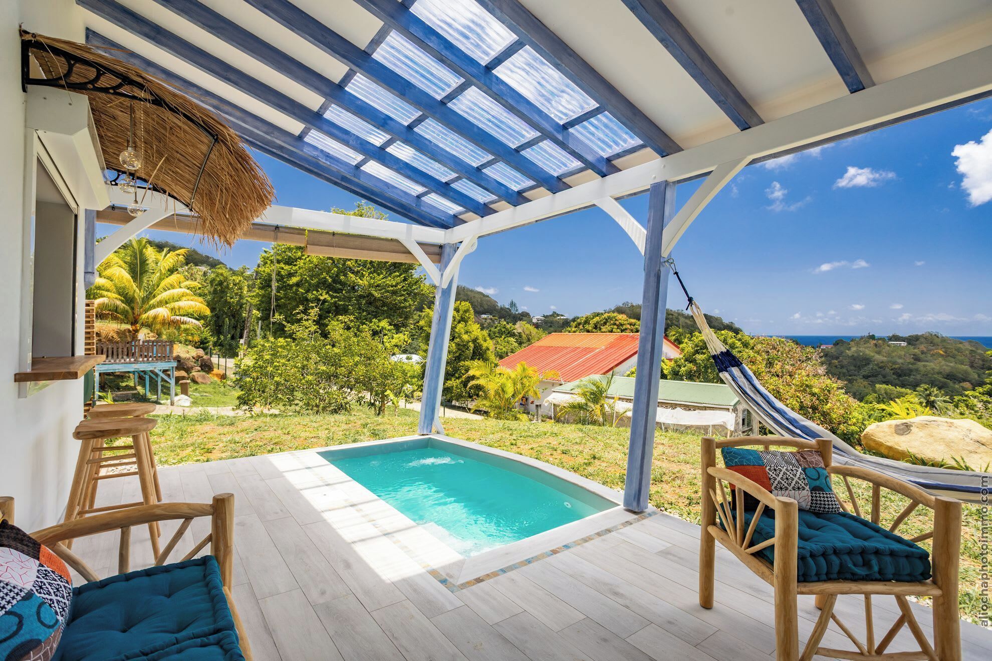 Un espace extérieur abrité comprenant une piscine, des sièges et une vue sur le paysage.