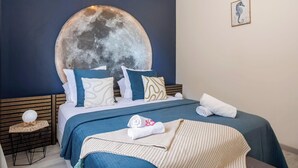 A bedroom with a large moon-like artwork on the wall, a bed with blue bedding, and a small bedside table with a spherical object. - La Villa de Solange - Azur (La Trinité)
