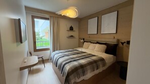A modern bedroom with a bed, a desk, and a window. - T2 au pied des pistes | Piscine sur place | Garage (Alpe d'Huez)