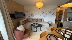 Un salon moderne avec un canapé, une table basse et un téléviseur fixé au mur.