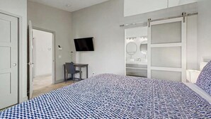 Una camera da letto con un letto, una scrivania, una TV e un cabina armadio.