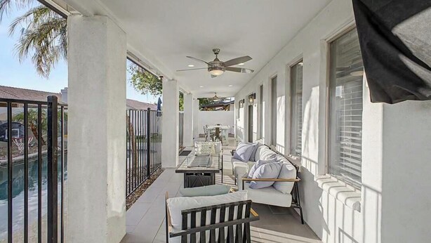 Un balcone con ventilatore a soffitto, un divano e un tavolo da pranzo.
