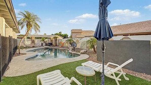 Un giardino sul retro con piscina, sedie a sdraio e canestro da basket.