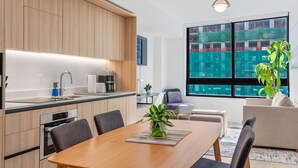 Una cocina moderna con armarios de madera, horno empotrado y comedor con mesa y sillas.