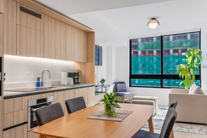 Eine moderne Küche mit Holzschränken, einem Einbauofen und einem Essbereich mit Tisch und Stühlen.