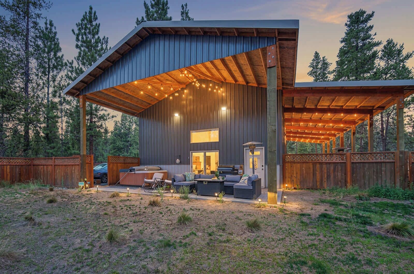 Eine moderne Außenpatio mit überdachter Sitzecke, einem Grill und Blick auf den umliegenden Wald.