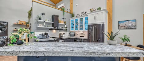 Una cocina moderna con encimera de granito, electrodomésticos de acero inoxidable y detalles de madera.