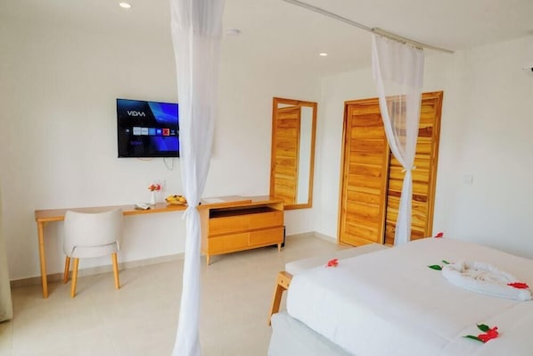 Una habitación de hotel con cama, escritorio, silla, televisor y armario.