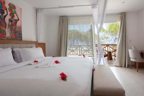 Habitación de hotel con una cama grande, vistas al exterior y un comedor.