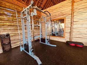 A gym with a wooden interior, a weightlifting machine, and a mirror. - Royal Mandarin Hotel & Resort (Kiwengwa)