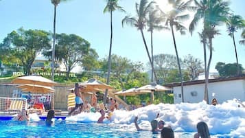 Uma área de piscina com palmeiras, guarda-sóis e uma placa do Hotel Royal Caribbean.