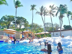 Un área de piscina con palmeras, sombrillas y un letrero del Hotel Royal Caribbean.