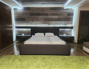 Ein modernes Schlafzimmer mit einem großen Bett, zwei Nachttischen und einer Holzwandverkleidung.