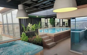 Ein Poolbereich auf dem Dach mit Whirlpools, Sitzgelegenheiten und Topfpflanzen.