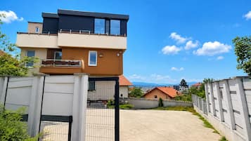 Un immeuble résidentiel moderne à deux étages, doté d’une entrée sécurisée et offrant une vue dégagée sur le quartier environnant.
