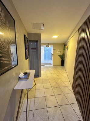 A hallway with a reception desk, a door marked 'AVISO,' and a potted plant. - Fully furnished loft 210 in the Fazenda neighborhood. (Itajaí)