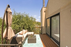 A balcony with a sofa, cushions, a table, and a patterned rug. - Black Hills Townhome -Community Pool-Near Downtown (Rapid City)