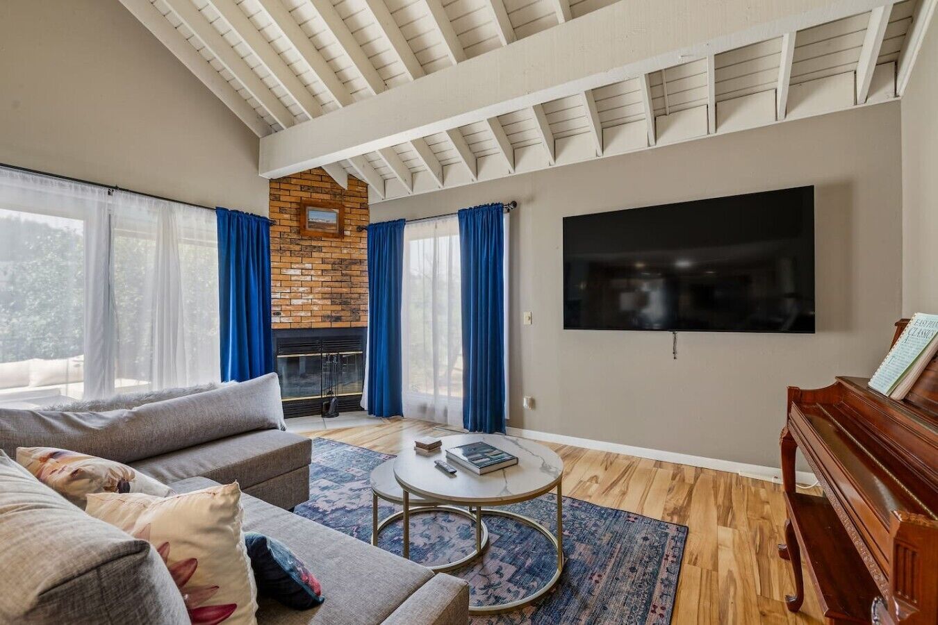 Ein Wohnzimmer mit Kamin, Fernseher, Klavier und einer Couch.