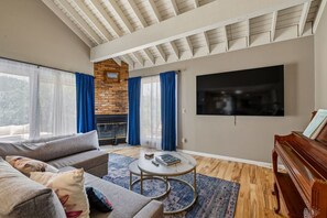 A living room with a fireplace, a television, a piano, and a sofa. - Black Hills Townhome -Community Pool-Near Downtown (Rapid City)