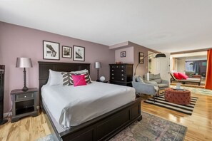 Ein Schlafzimmer mit einem großen Bett, einem Schminktisch, einem Sessel und einem kleinen Hocker.