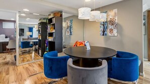 A modern dining area with a round table, blue upholstered chairs, and a bookshelf in the background. - Black Hills Townhome -Community Pool-Near Downtown (Rapid City)