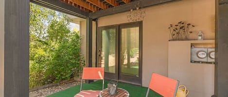 Un espace extérieur abrité avec deux chaises, une petite table et une carafe d’eau.