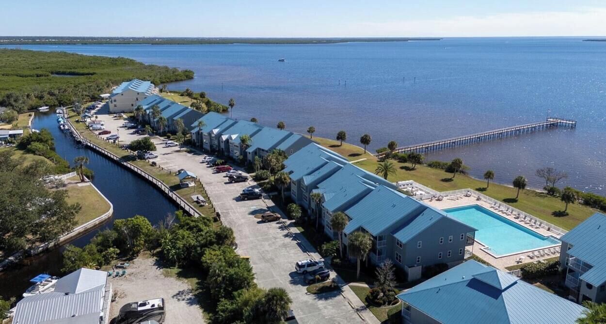 Een hotel aan het water, met een lang gebouw, een zwembad en een steiger die in het water reikt.