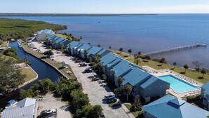 Un hôtel situé au bord de l’eau, avec un long bâtiment, une piscine et une jetée qui s’avance dans l’eau.
