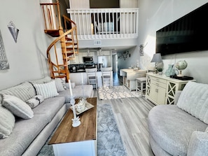 A spacious living area with a high ceiling, a wooden spiral staircase, a kitchen, and a dining area. - Superb 2-bedroom condo with large pool in wonderful Port Charlotte (Port Charlotte)